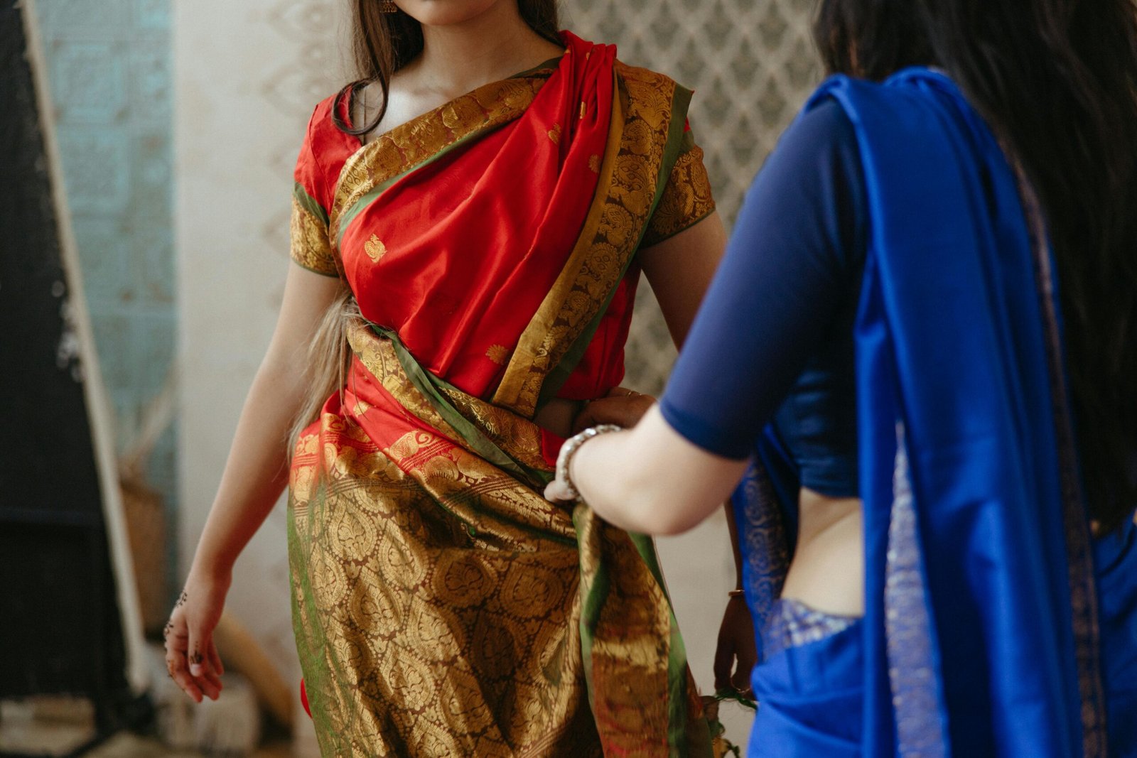 Women wearing vibrant sarees indoors, highlighting traditional Indian attire and culture.